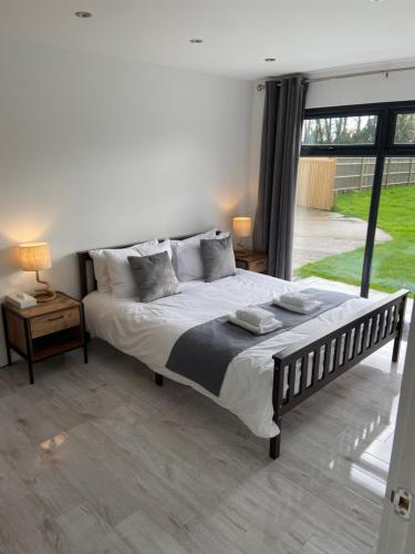 a bedroom with a large bed and a large window at Court Lane Stables - Premium Rural Retreat with Hot Tub in Hadlow