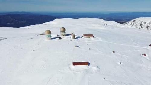a snow covered mountain with buildings on top of it at Orion Guesthouse Telhado in Fundão