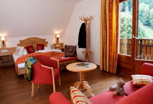 a bedroom with a bed and a table and chairs at Logis Auberge Du Mehrbachel - Hôtel & Restaurant in Saint-Amarin