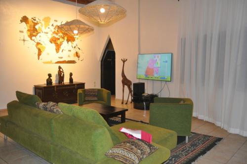 a living room with two green couches and a tv at Amani Paradise - Luxury Villas in Diani Beach