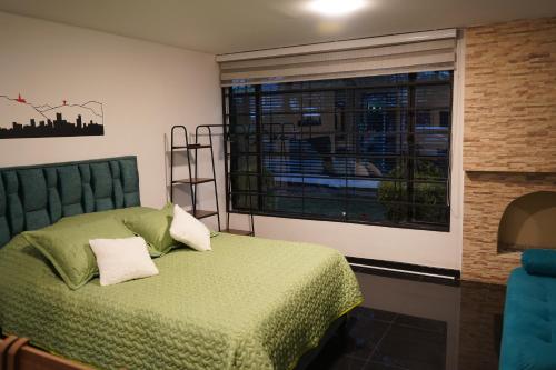 a bedroom with a green bed and a window at Apartamento Astromelia - Casa Tartaruga Bogotá in Bogotá