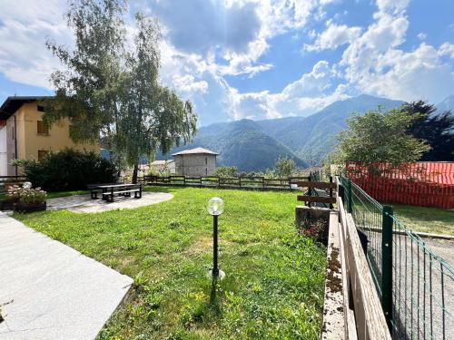 a park with a bench and a fence and mountains at Condominio Le Dolomiti in Forni di Sotto