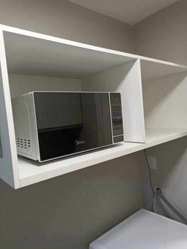 a microwave on a shelf in a kitchen at Golden Gate Residence Service in Vitória