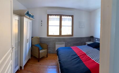 una camera da letto con un letto, una sedia e una finestra di Charmant logement tout confort avec terrasse a Saint-Amand-les-Eaux