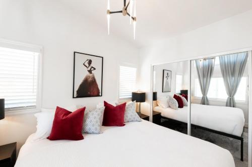 biała sypialnia z 2 łóżkami i czerwonymi poduszkami w obiekcie Elegant Courtyard Cottage Ruby w mieście Reno