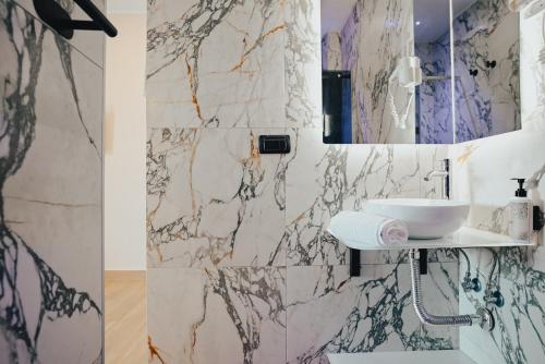 a bathroom with a sink and a marble wall at Puteoli Palace Hotel in Pozzuoli