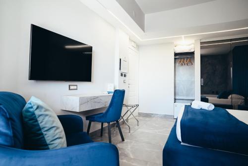 a living room with blue chairs and a tv at Puteoli Palace Hotel in Pozzuoli