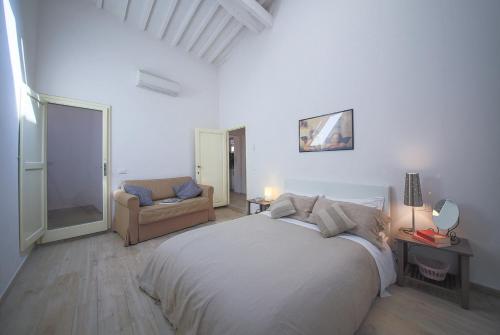 ein weißes Schlafzimmer mit einem großen Bett und einem Sofa in der Unterkunft Apartments Florence Pandolfini Roof in Florenz