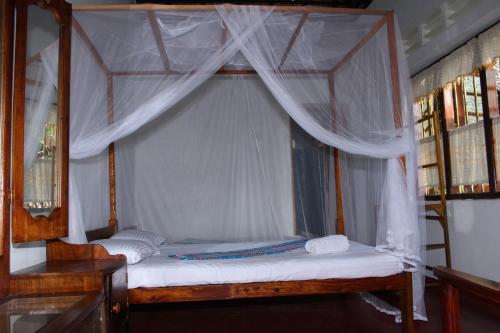 a bedroom with a canopy bed with white curtains at Abberny villa in Midigama