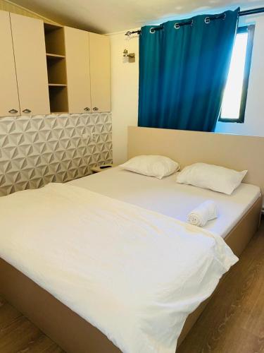 a bedroom with a large bed with a blue curtain at Stanford Aparthotel Gara de Nord in Bucharest