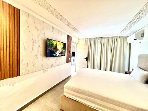 a hotel room with a bed and a tv on a wall at SABOR FAMILY APARTS -Jaouharat Al Atlas in Marrakech