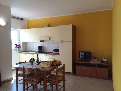 a kitchen with a table and chairs and a kitchen with yellow walls at Residence Le Azalee & SPA in Vercana