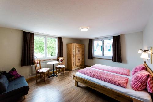 a bedroom with a bed and a couch and windows at Hotel Brienzerburli in Brienz