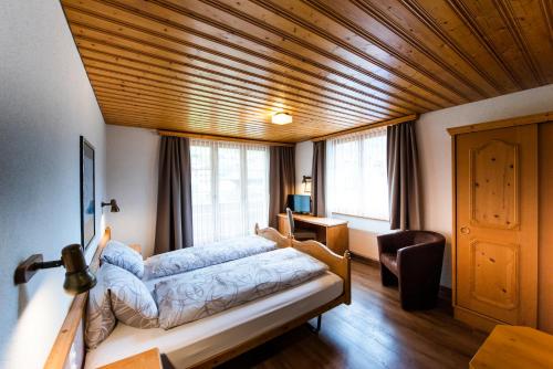 a bedroom with a bed with a wooden ceiling at Hotel Brienzerburli in Brienz