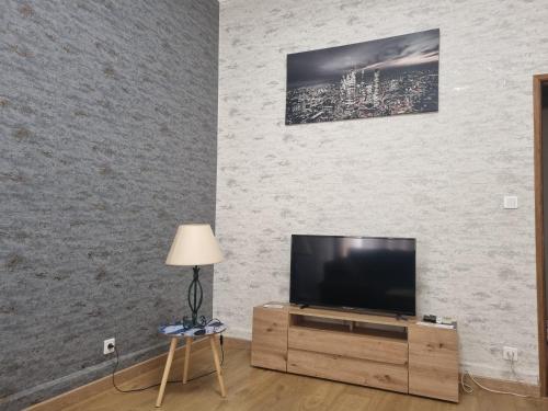 a flat screen tv sitting on top of a wooden entertainment center at Appartement au cœur de la ville in Chalon-sur-Saône