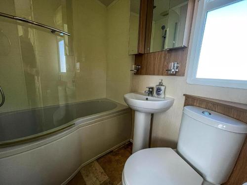 a bathroom with a toilet and a sink and a tub at Lovely Caravan With Decking At Manor Park, Near Hunstanton Beach Ref 23034C in Hunstanton