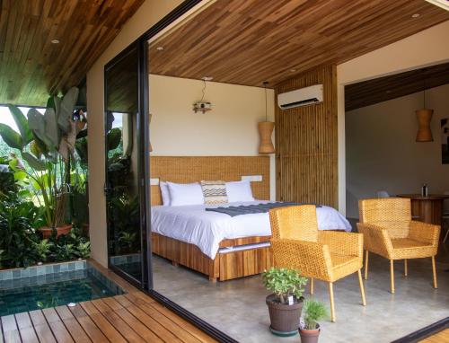 a bedroom with a bed and chairs on a balcony at Scenic Volcano Villas with Hot Tub in Fortuna