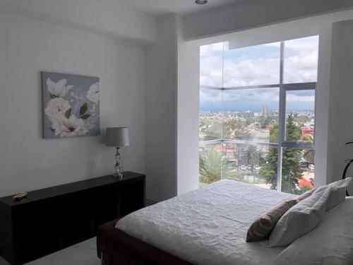 ein Schlafzimmer mit einem Bett und einem großen Fenster in der Unterkunft Apartamento de lujo Col La Paz 201 in Momoxpan