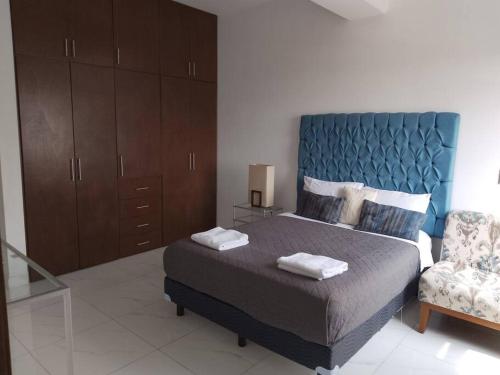 ein Schlafzimmer mit einem großen Bett und einem Stuhl in der Unterkunft Apartamento de lujo Col La Paz 201 in Momoxpan