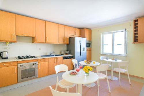 a kitchen with two tables and chairs and a refrigerator at Urban Bliss Guesthouse II in Faro