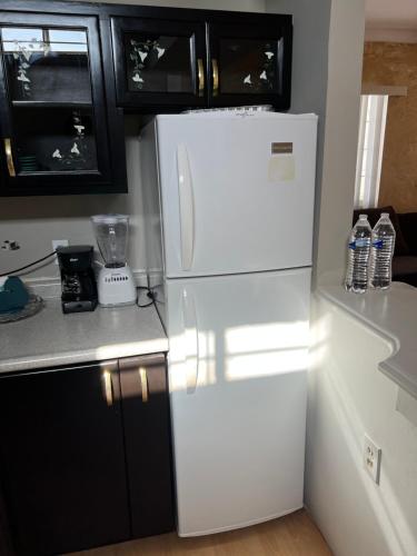 a white refrigerator in a kitchen with black cabinets at Apartment Rosarito Beach Downtown A in Rosarito