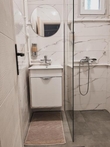 a white bathroom with a sink and a shower at Prenoćište Katarina JUGOVO in Smederevo