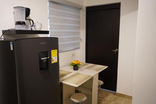 a kitchen with a black refrigerator and a table at Apartamento Flor de Azúcar - Casa Tartaruga Bogotá in Bogotá