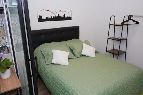 a bedroom with a green bed with two pillows at Apartamento Flor de Azúcar - Casa Tartaruga Bogotá in Bogotá