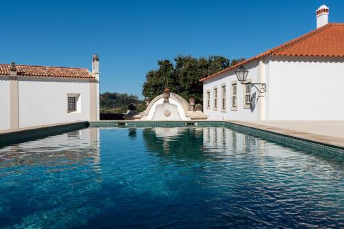 a swimming pool in front of two white buildings at Cazal d'Oliveira in Granja