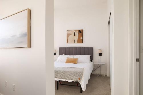 a white bedroom with a bed and a table at Modern Studio Apt with Rooftop, Gym, and Parking in Milwaukee