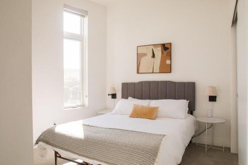a white bedroom with a large bed and a window at Modern Studio Apt with Rooftop, Gym, and Parking in Milwaukee