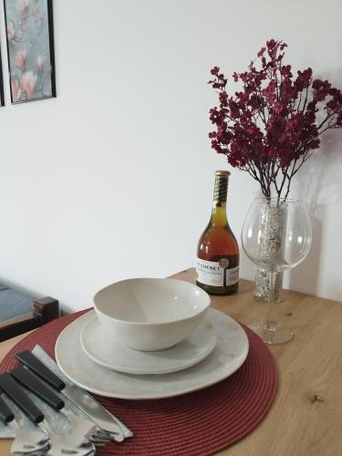 a table with a bowl and plates and a bottle of wine at Studio29 2 in Ruma