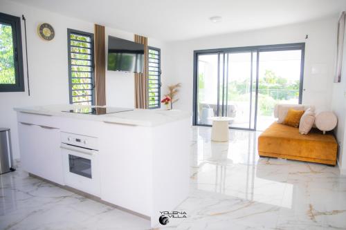 a white living room with a couch and a kitchen at Yolena Villa in Le Gosier