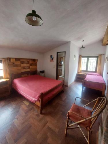 a bedroom with a large red bed and a chair at Hostel El Rincon in Villa General Belgrano