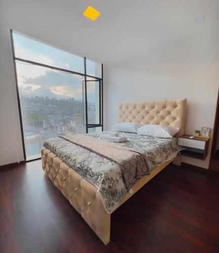 a bedroom with a large bed with a large window at Amplio Departamento Familiar en Loja in Loja