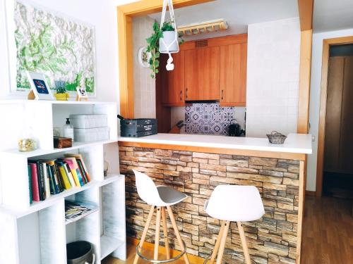 a kitchen with a counter and two white stools at ÁLIGA CONFORT Vistas a pie de pistas in El Tarter