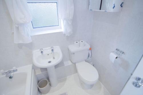 a white bathroom with a toilet and a sink at 2 Bed House - BHX - NEC in Solihull