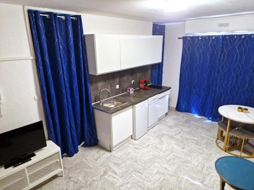 Elle comprend une petite cuisine avec des rideaux bleus et un évier. dans l'établissement Studio proche centre avec terrasse, à Draguignan