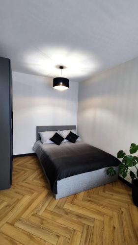 a bedroom with a bed with black sheets on a wooden floor at Apartament Park Chorzów, FV, bezpłatny parking, klimatyzacja in Chorzów