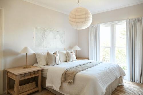 a bedroom with a white bed with a large window at Tyntynder Coastal Beach House with Panoramic Views and Stunning Sunsets in Ocean Grove