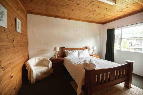 a bedroom with a bed and a chair and a window at Central Two Bedroom Apartment With Mountain Views in Mount Beauty
