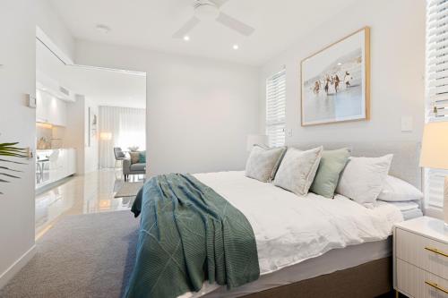 a white bedroom with a bed and a living room at Bokarina Beach Apartments, an Ascend Collection Hotel in Bokarina