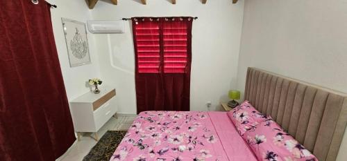 a bedroom with a pink bed and a red window at Dyna condo one in Sainte-Rose