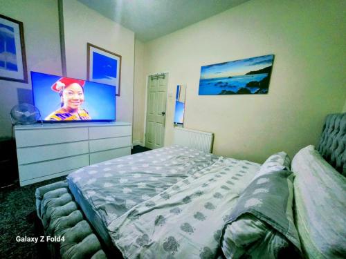 a bedroom with a bed and a flat screen tv at Luxury King-size Rm in Bolton