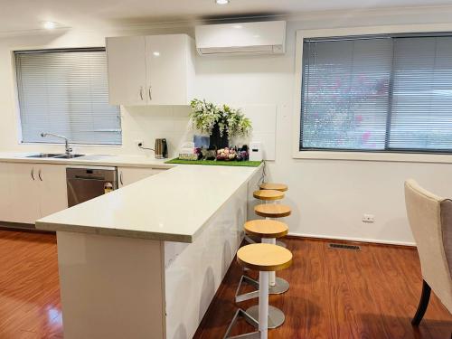 a kitchen with white cabinets and a counter with stools at D130 The Link Fantasy Place in Keilor