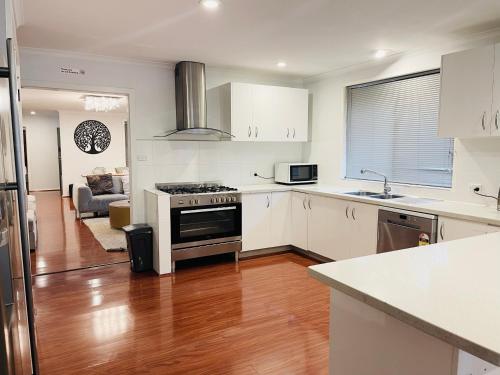 a kitchen with white cabinets and a stove top oven at D130 The Link Fantasy Place in Keilor