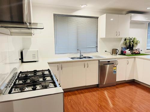 a kitchen with white cabinets and a stove top oven at D130 The Link Fantasy Place in Keilor
