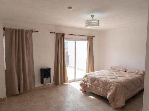 a bedroom with a bed and a large window at Descubre Salta desde este Duplex acogedor in Salta