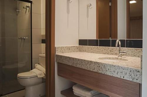 a bathroom with a sink and a toilet and a mirror at Praias do Lago Eco Resort - Central de Reservas in Caldas Novas