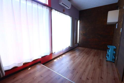 a room with a large window and a wooden floor at ゲストハウスAgain in Hitoyoshi